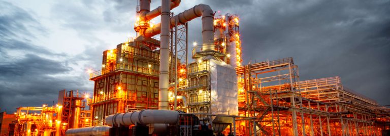 Vista panorâmica de um complexo industrial de grande dimensão ao entardecer.